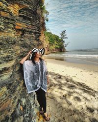 Woman standing at beach against sky