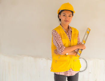 Portrait of smiling girl standing against yellow wall
