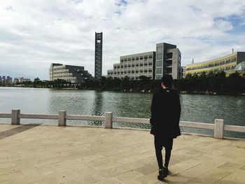 Rear view of man standing by railing against river