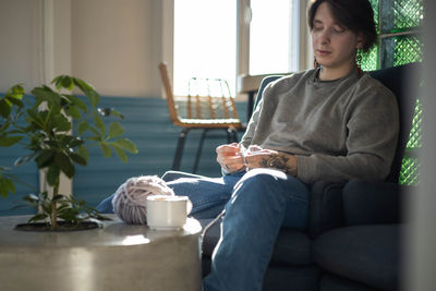 Young woman using laptop while sitting on sofa at home