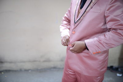 Midsection of woman standing by pink umbrella in city