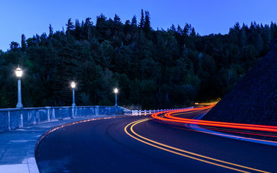 Light trails on road against sky at night