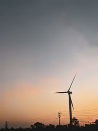 Silhouette wind turbines on landscape against sky during sunset