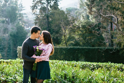 Couple kissing while standing against plants in park