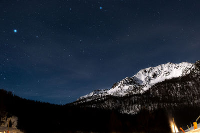 Astrophotography at alps - low angle view of snowcapped mountain against sky at night