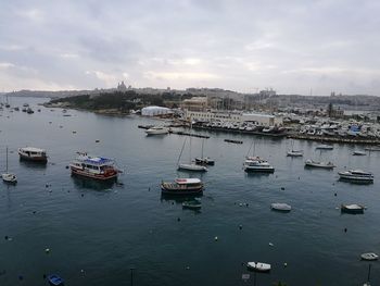 Boats moored at harbor against sky