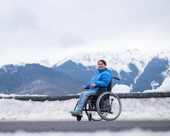 Rear view of man riding bicycle on snowcapped mountain