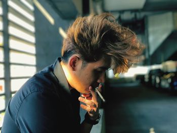 Side view of young man smoking cigarette in city