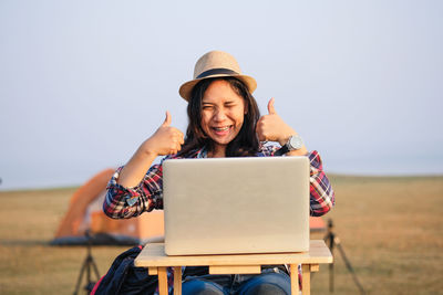 Young woman using mobile phone while sitting on land