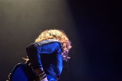Low angle view of female guitarist playing guitar during concert