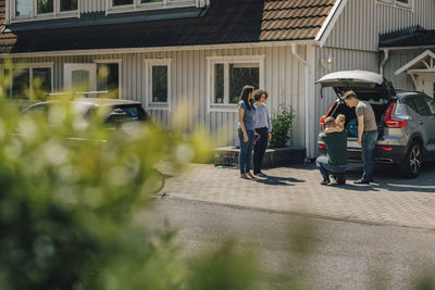 Gay father embracing son while lesbian couple standing by car during sunny day