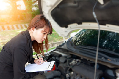 Woman holding camera while sitting in car