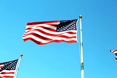 Low angle view of flag flags against clear blue sky