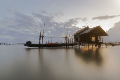 Stilt houses by sea against sky