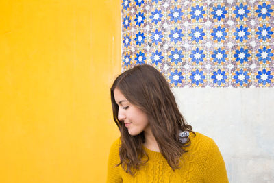 Portrait of a beautiful young woman against yellow wall