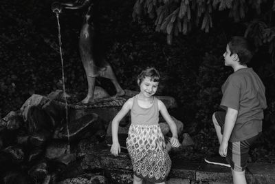 Siblings enjoying against trees in park