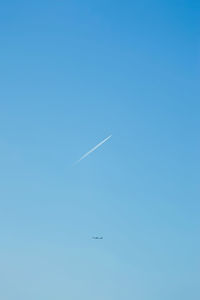 Low angle view of airplane flying against clear blue sky