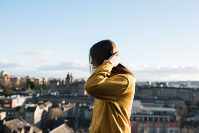 Woman standing in city against sky