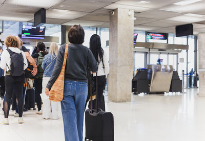 Woman with luggage standing in a line at airport.