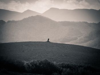 Silhouette person on mountain against sky