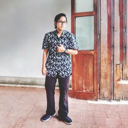 Portrait of young man standing against wall