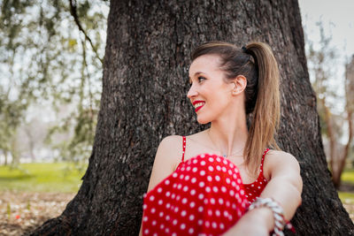 Smiling woman sitting tree trunk on land 