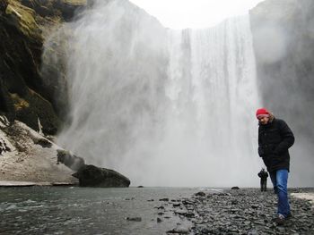 Man walking against waterfall during winter