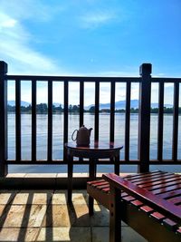 Woman sitting on table by sea against sky