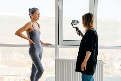 Side view of woman standing against window