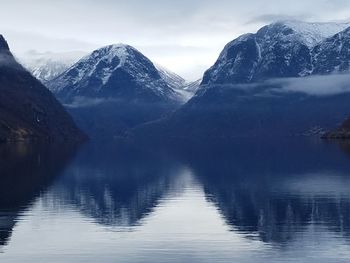 Scenic view of lake by snowcapped mountains against sky