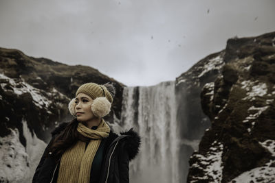 Young woman looking away while standing on mountain against sky