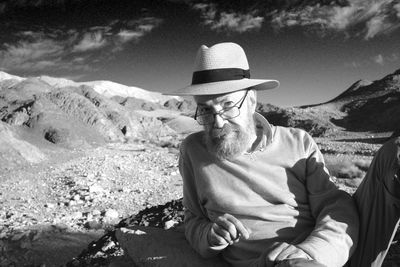 Rear view of man wearing hat while sitting on mountain