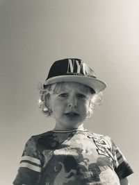 Low angle portrait of cute boy standing against sky