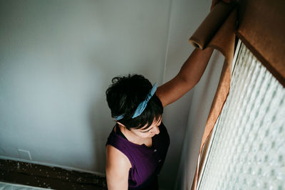 Rear view of woman standing against wall at home