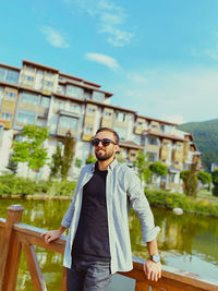 Portrait of young man standing against bridge against sky