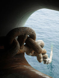 Close-up of rusty chain against sea