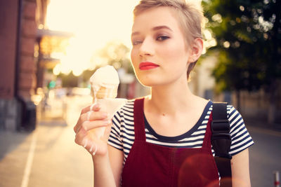 Portrait of woman holding ice cream in city