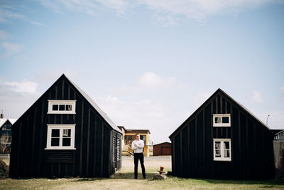 Man standing outside of shed against sky