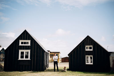 Woman standing outside house against sky