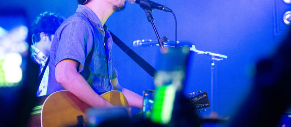 Midsection of man playing guitar at music concert