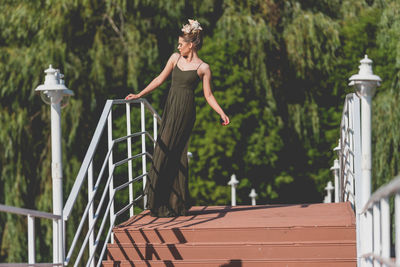 Woman standing by railing against plants