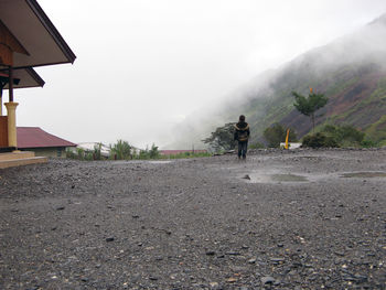 Rear view of boy walking against foggy weather