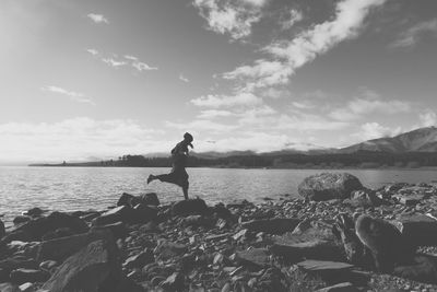 Woman standing on rock at beach against sky