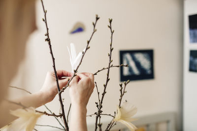 Hands decorating twigs with feathers