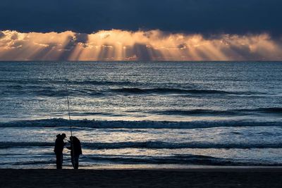 Silhouette of people on beach at sunset