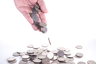 Cropped hand pouring coins on white background