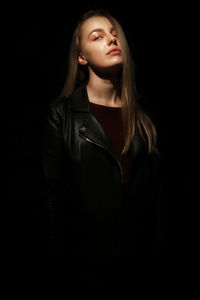 Portrait of fashionable woman standing against black background