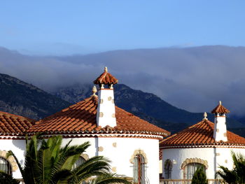 High section of houses by mountain against cloudy sky