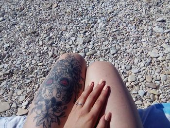 Low section of woman legs on pebbles at beach