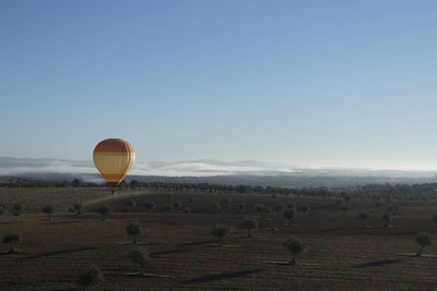 Hot air balloon flying over landscape against clear sky
